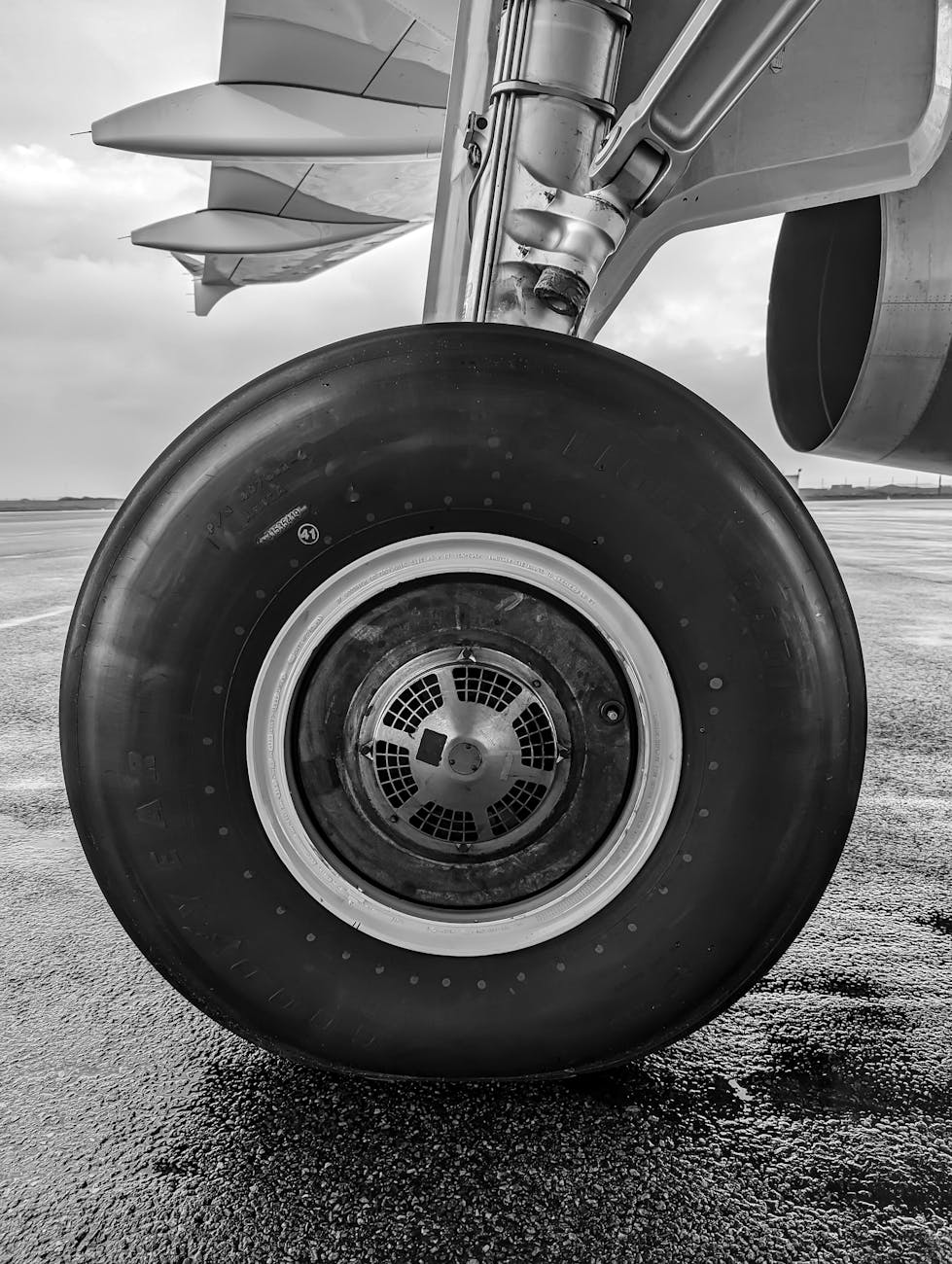 black and white photo of an airplane wheel on a airport runway